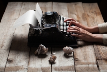 Hands writing on old typewriter over wooden table background