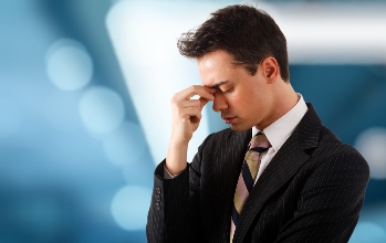 Young stressed and tired businessman. Blue blurred background.